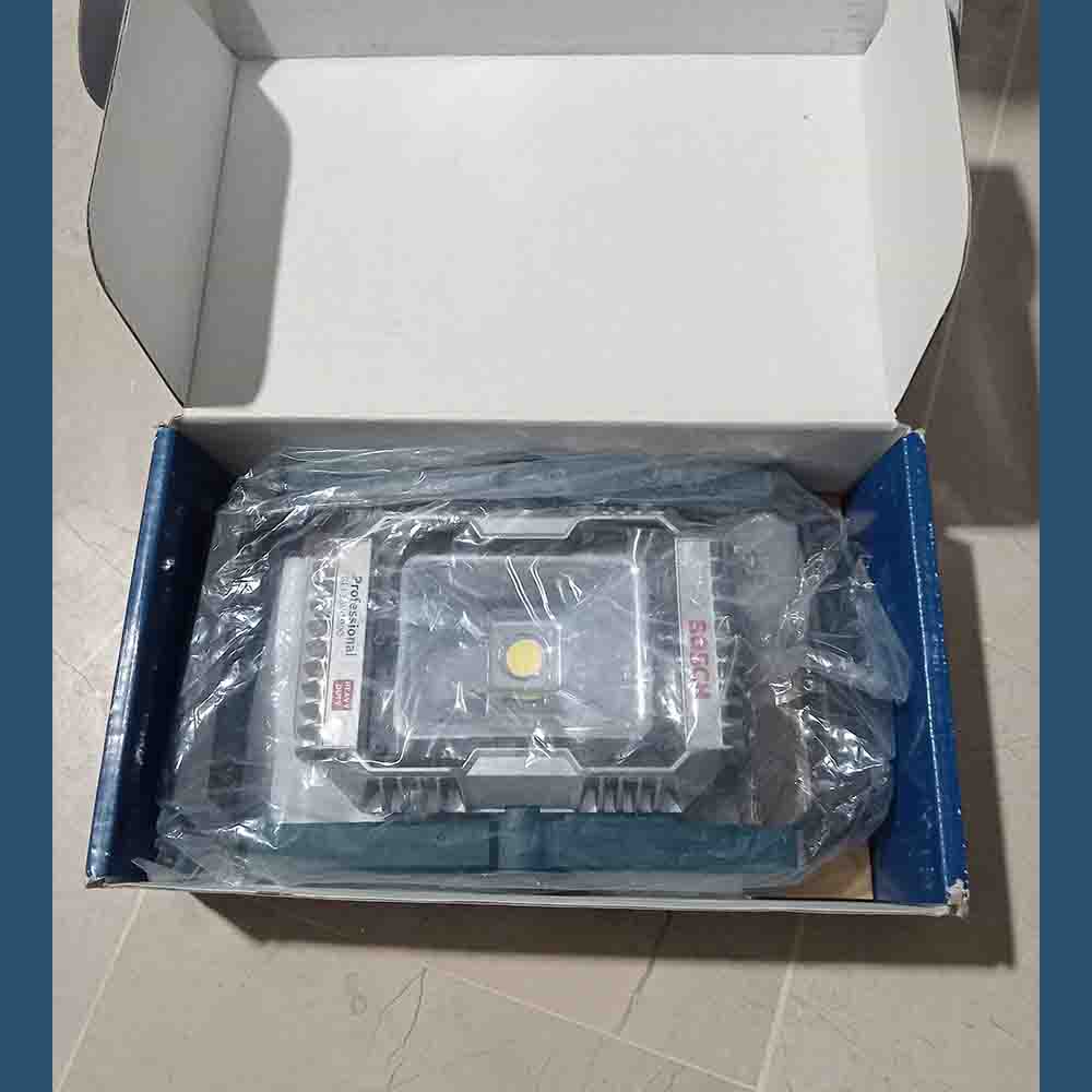 Electrical component in a plastic bag inside an open box on a tiled floor.
