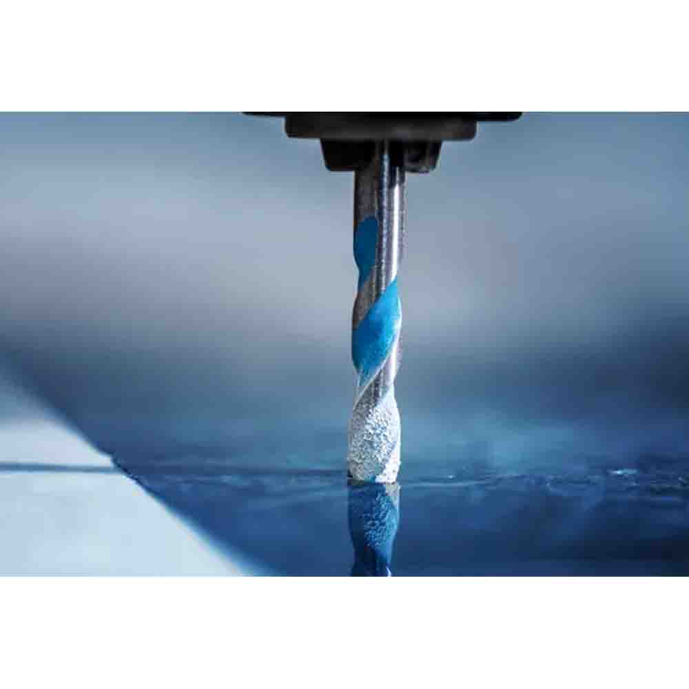 Drill bit in action on a blue surface